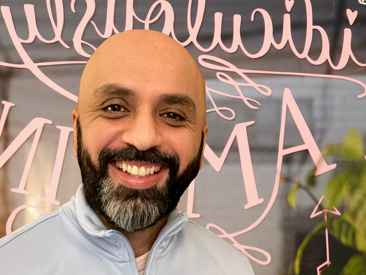 Portrait of artist Ally Noormohamed smiling outdoors